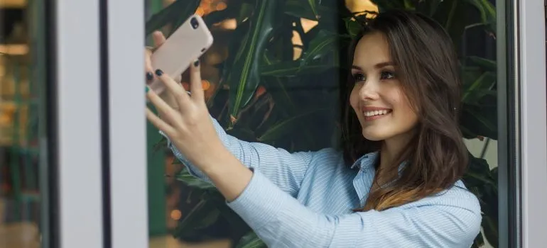 A woman holding a phone and smiling, trying to overcome post-moving depression.