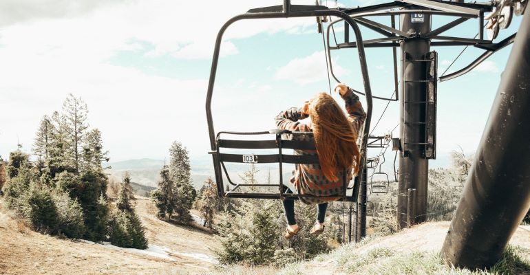 Woman in Brown Long Sleeve Shirt and Black Pants on Black Metal Frame
