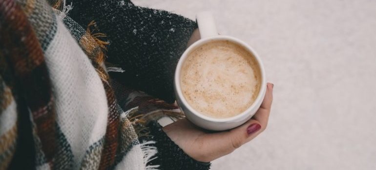 A woman holding a cup of coffe in the snow.