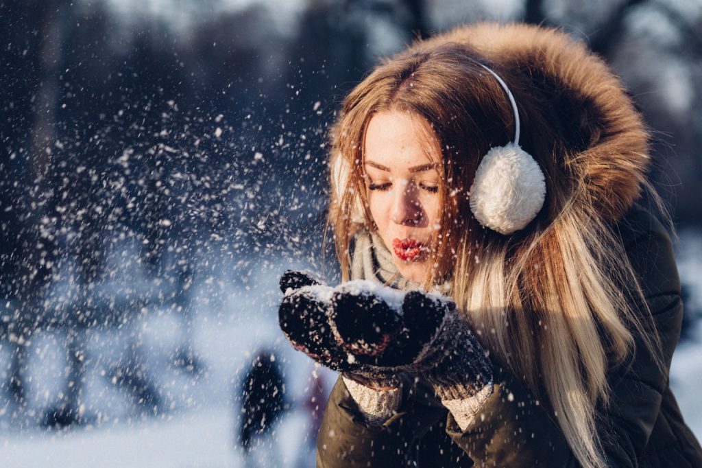 A happy woman having fun in the snow after moving from Idaho to Alaska.