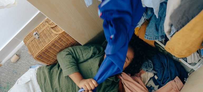 woman on floor covered in clothes