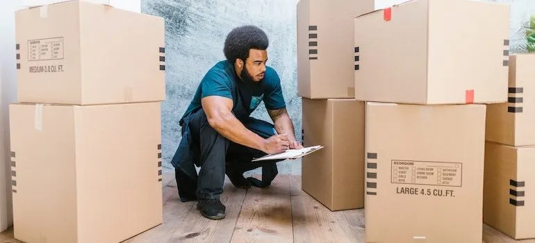 man making notes on a clipboard surrounded by boxes
