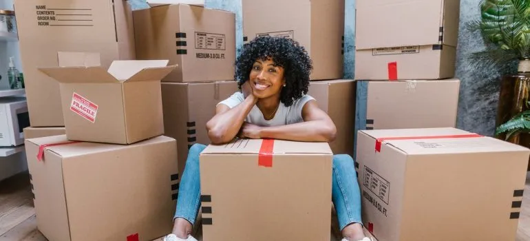 A smiling woman surrounded by moving boxes