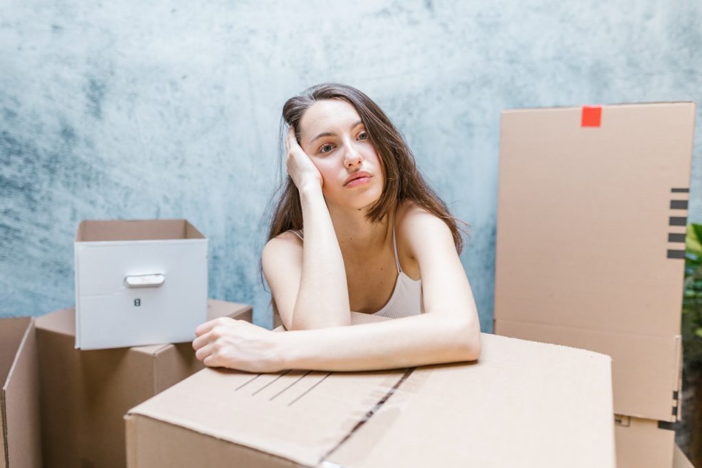 Woman leaning on a box is dealing with post-moving anxiety