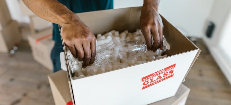 hands putting glasses into a box