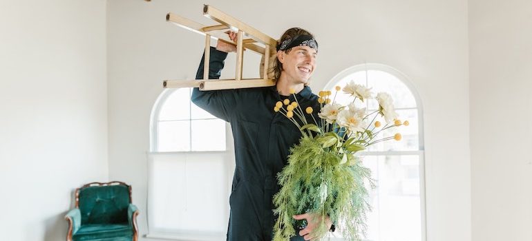 man holding a chair and flowers