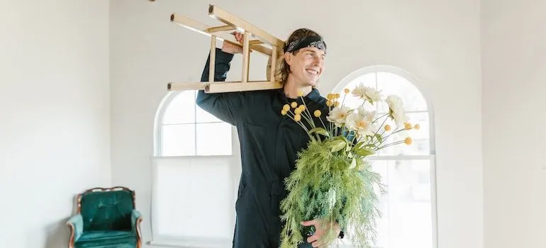 man holding a chair and flowers