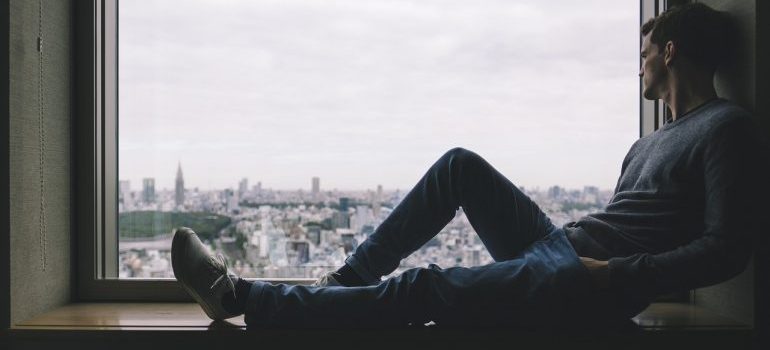 A man sitting on a window sill.