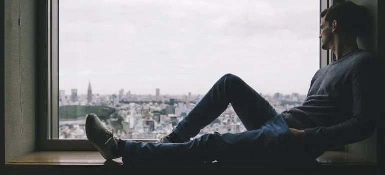 A man sitting on a window sill.
