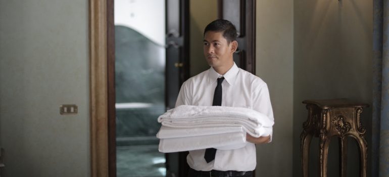 A man preparing to propperly store away sheets and bedding.