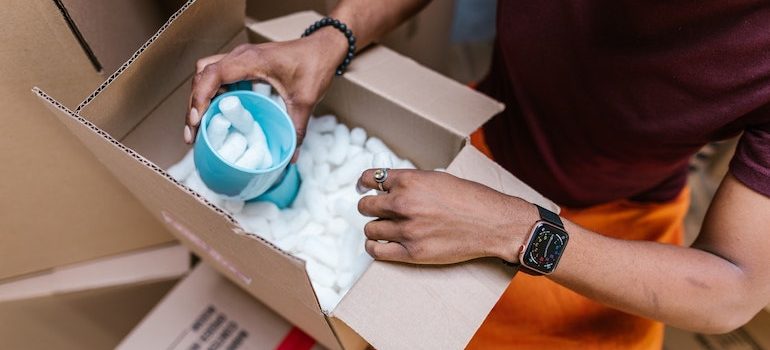 hand putting a cup into a box