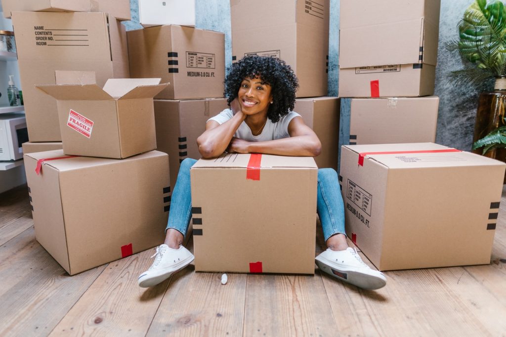 woman sitting on a floor surrounded by boxes is moving from Miami to Boise
