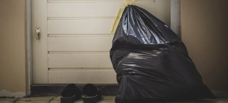 A black trash bag and slippers near the door.