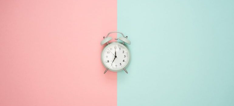 An alarm clock on a pink and blue surface.