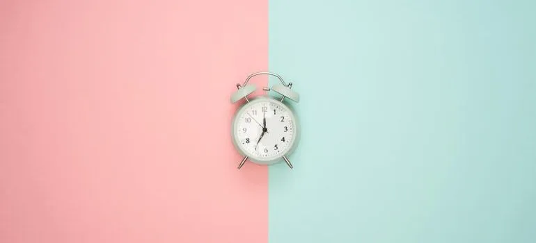 An alarm clock on a pink and blue surface. 