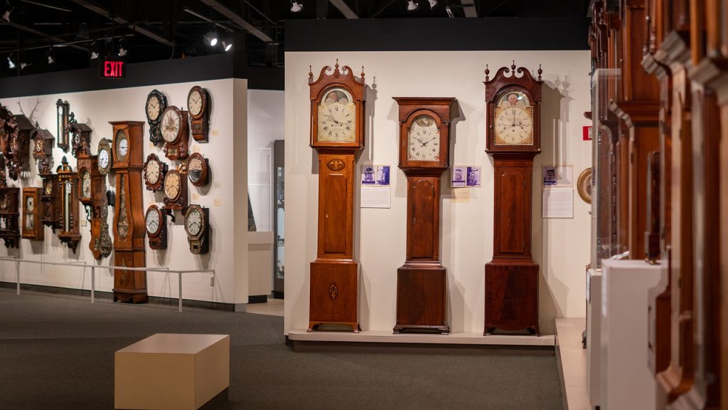 Three large grandfather clocks at the front of a store.