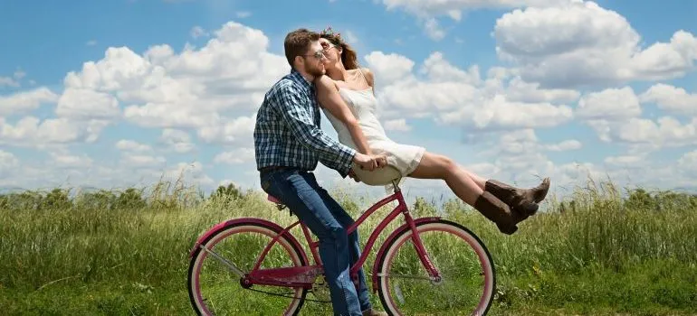 A couple on a bile in a field 