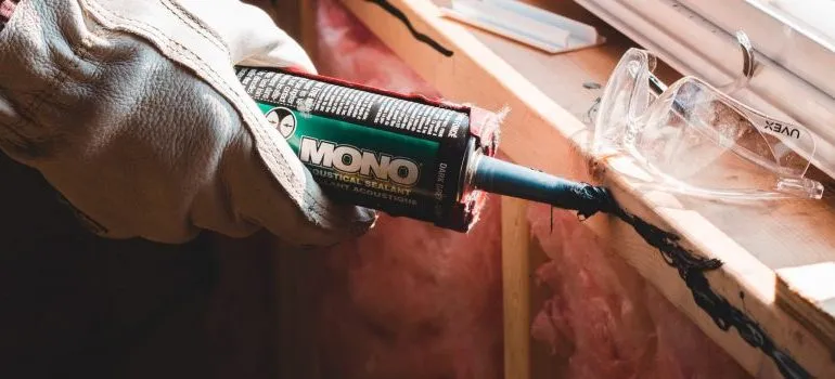 person using a sealant to repair a window