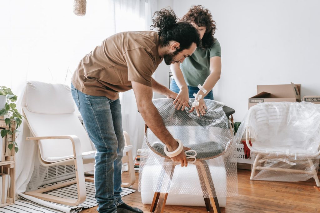A young couple wrapping a chair in stretch wrap