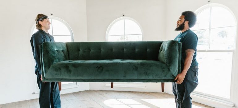 Movers carrying green sofa