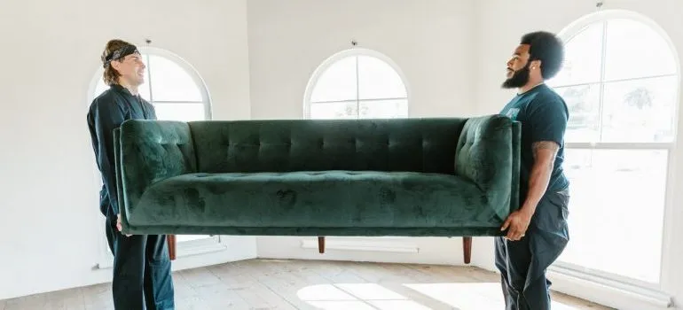 Movers carrying green sofa