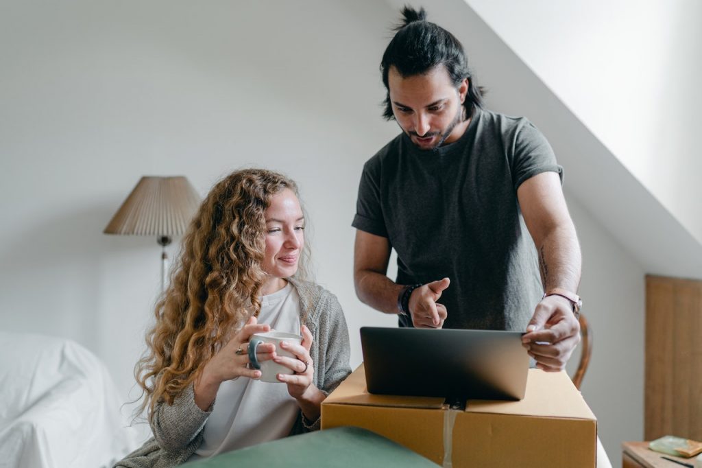 Young couple using laptop to research movers before hiring them