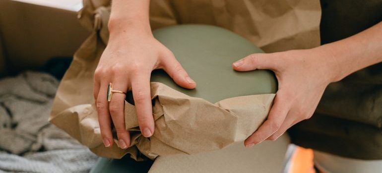 A woman wrapping an item in kraft paper.