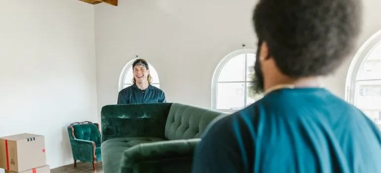 Two movers carrying a green couch