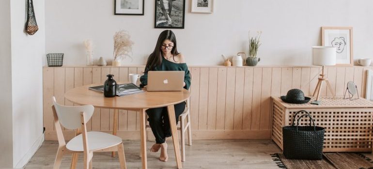 A woman with glasses using laptop to find minimalist moving tips.