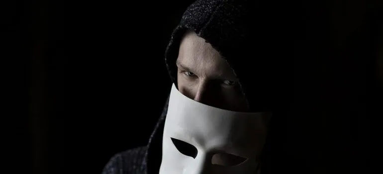 A shady character holding a white mask.