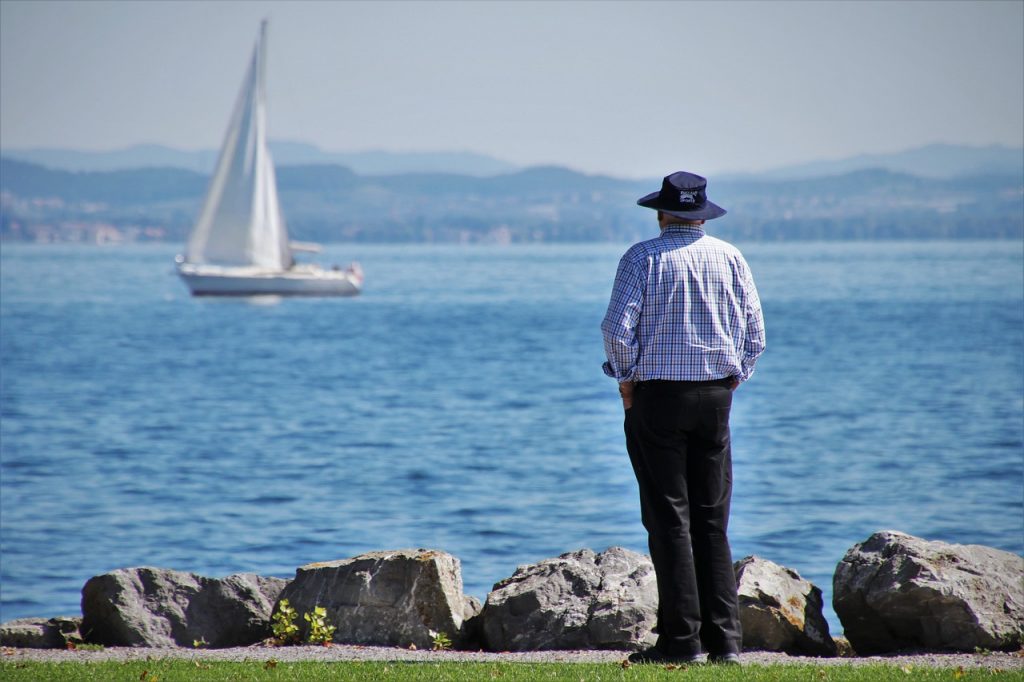A senior citizen standing in front of a lake.