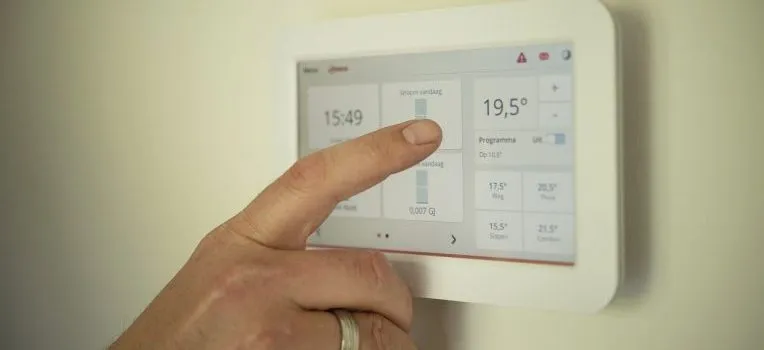 A person's hand setting up a thermometer on a wall