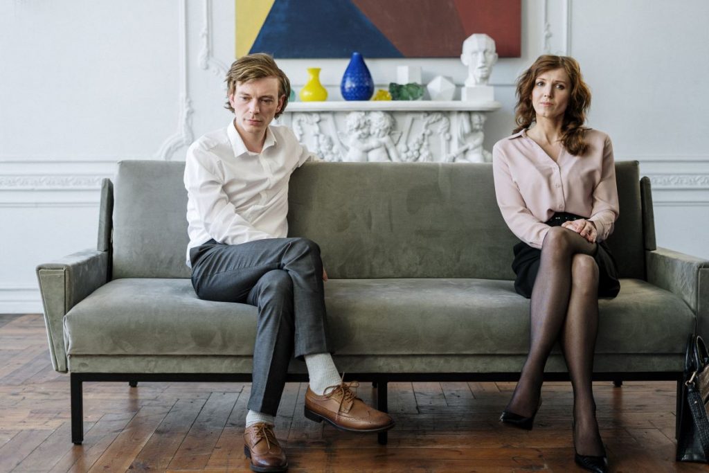A distanced couple on a sofa considering the struggle of moving due to divorce