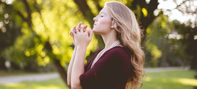 a woman outdoors, seemingly praying