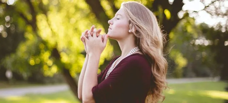a woman outdoors, seemingly praying