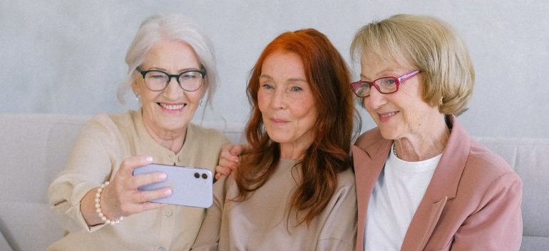 Three older women take selfies.