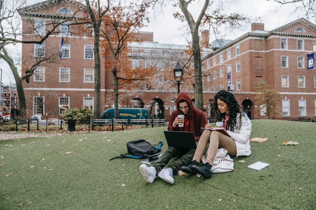 Students sit on the grass and study.
