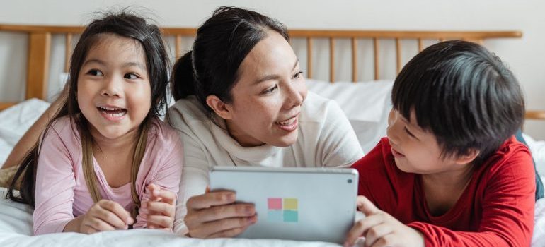 woman and two kids looking at a tablet