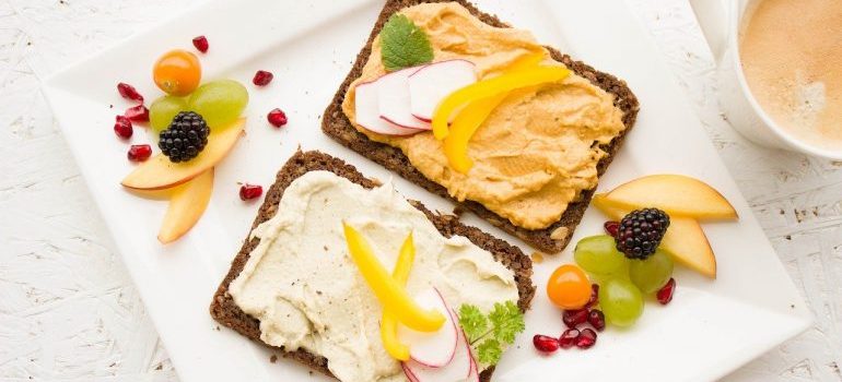 Two pieces of bread and fruit on a plate.