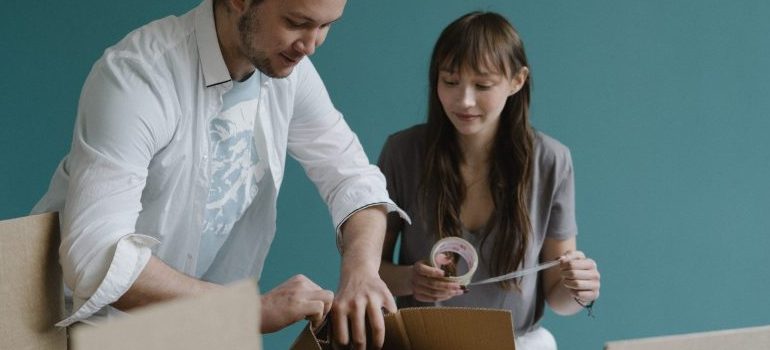a couple packing a cardboard moving box