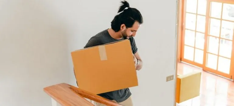 person holding a box close to him, showcasing one of the ways to approach heavy lifting without injuring yourself
