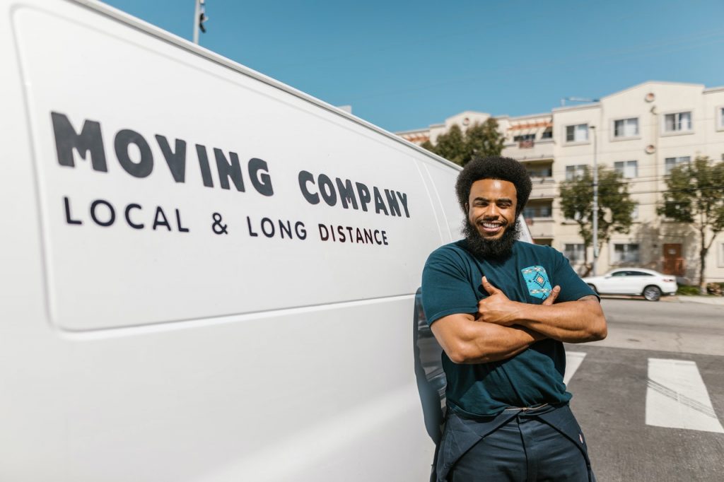 A mover posing next to a moving van.