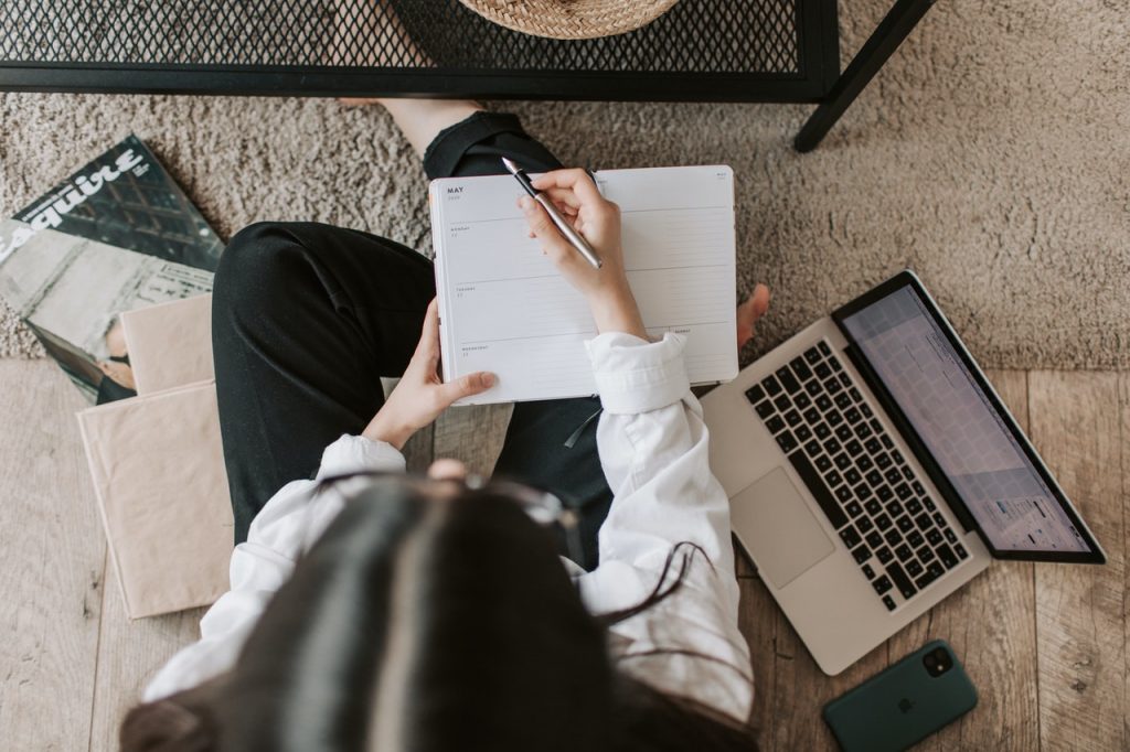 A woman holding a pen and paper to make a timeline for moving abroad