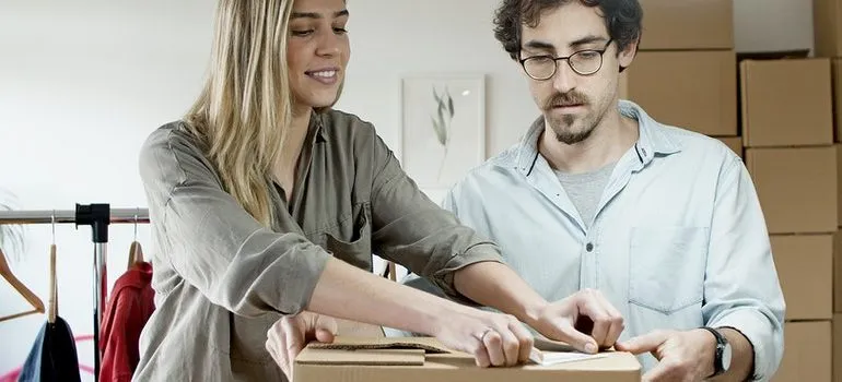 A man and a woman packing a box for their office move.