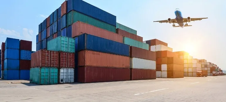 Freight forwarding containers with an airplane flying over them.