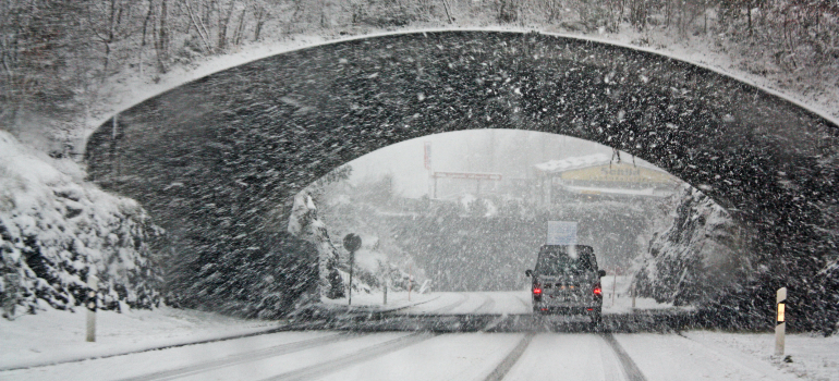 car driving down the road during a blizzard