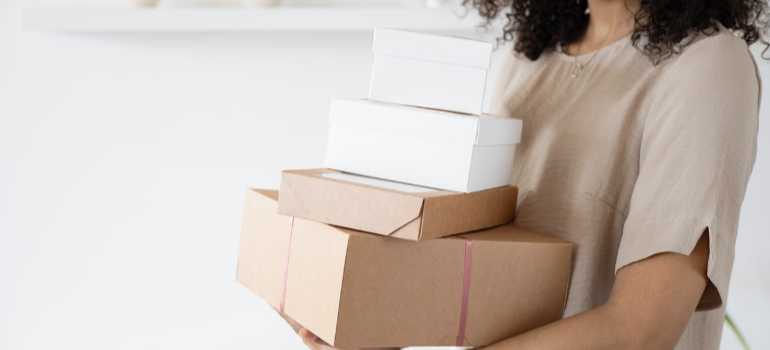 a woman holding boxes trying to maintain productivity while relocating an office