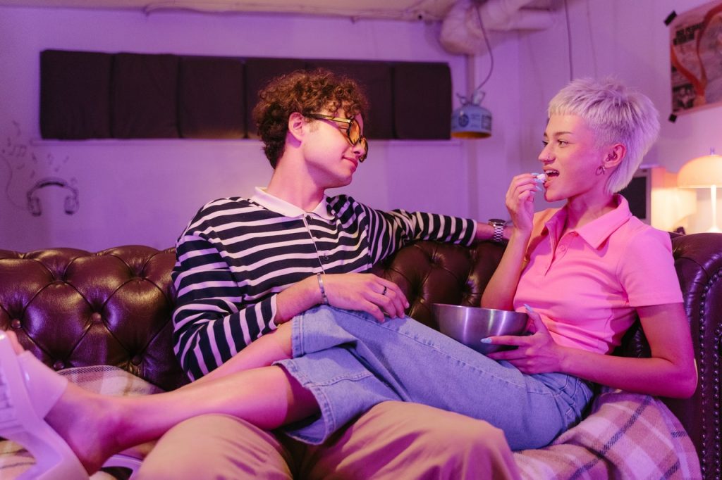 couple on a couch talking about how to merge two homes when moving in together