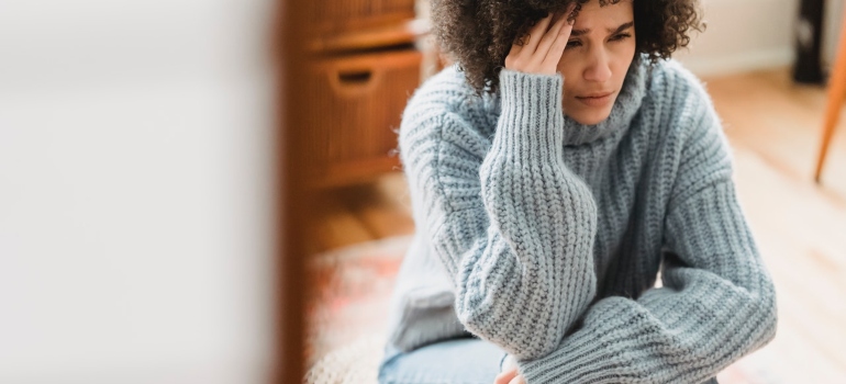 A woman having a headache thinking about disadvantages of hiring moving brokers