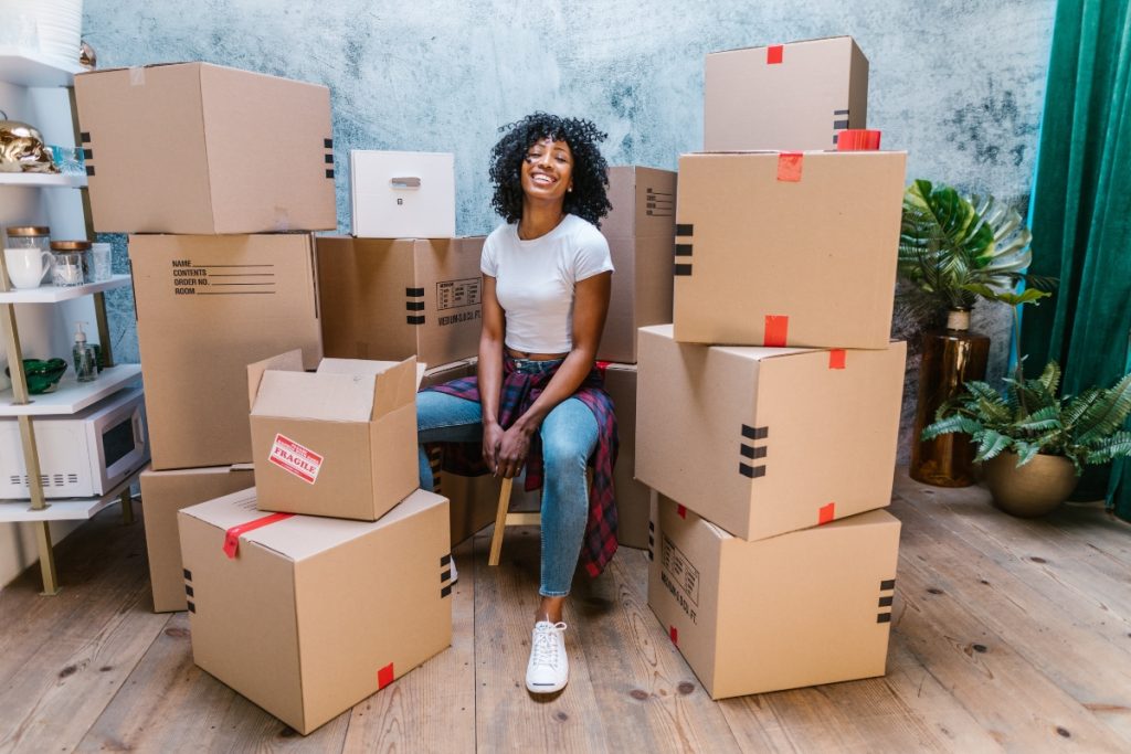 happy black woman surrounded by cardboard boxes